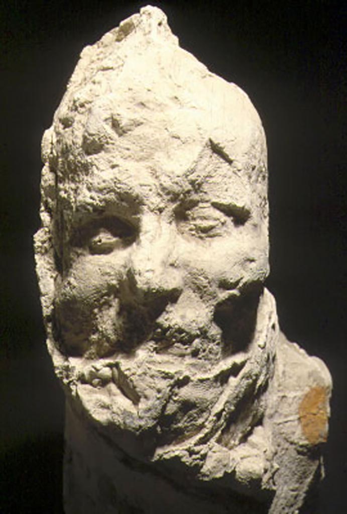 Pompeii, September 2015. Plaster cast of victim numbered 16, found 12th March 1890 outside of the Porta Stabiana.
On display as an exhibit in the Summer 2015 exhibition in the amphitheatre.
According to NdS, 12th March 1890, following the excavation of the agger on the right going out from Porta Stabiana, at a distance of about 72 metres from the Gate, the imprint of a human body was found in the compacted layer of ash. Sig. Salvatore Cozzi directed the operation to cast the plaster-cast.
The reproduction was one of the best and most successful made up until that time.
The cast represented a young slim male, lying on his left side, wrapped in a cloak and with short pants that exposed his legs below the knee.
The sandal he was wearing was clearly seen on his right foot. 
Nothing more could be said of the left leg because this and the hand turned out badly. Height 1.55 metres. 
See Notizie degli Scavi di Antichità, 1890, p. 128.
See Dwyer, E., 2010. Pompeii’s Living Statues. Ann Arbor: University of Michigan Press. (p.107 and fig.48).

