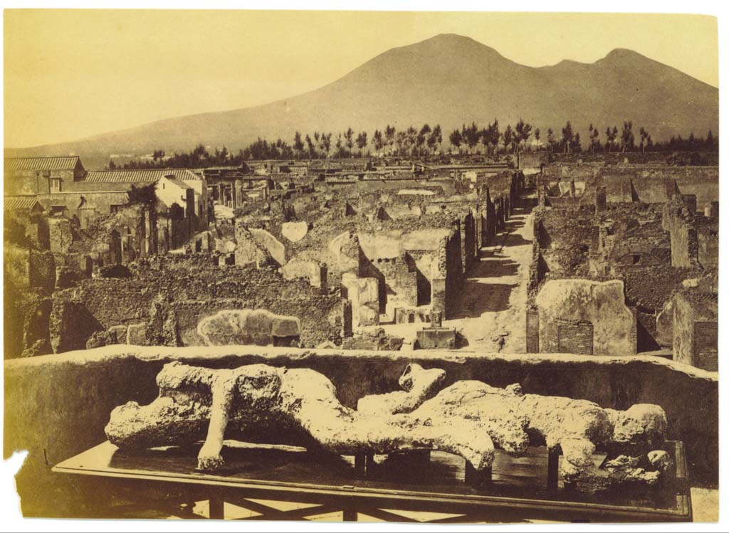 Plaster-casts of victims numbered 2 and 3, photographed on an upper floor (possibly from VII.6.7), looking north towards Vicolo di Modesto and Vesuvius.
Centre-left can be seen the rebuilt School of Archaeology on Via Consolare. Photo courtesy of Eugene Dwyer.
