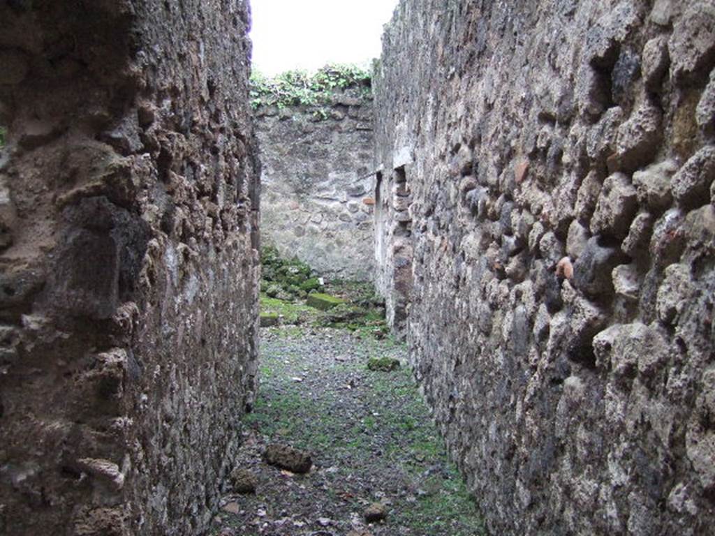 VII.10.3 Pompeii. December 2005. Corridor 18, looking south into room 19, the kitchen.
Directly ahead, in the south-west corner of the kitchen, was a small separate latrine. According to Boyce, in the kitchen was a lararium painting upon a white background, depicting Fortuna. In her left hand she held a rudder, her right hand extended above a globe which lay at her feet. The painting was incomplete, for on the right side the stucco showed that at least one more figure was to have been added.
Helbig 74.
See Boyce G. K., 1937. Corpus of the Lararia of Pompeii. Rome: MAAR 14. (p.69, no.308) 

According to Amoroso, from these service rooms, it was possible to exit the house in the direction of the Vicolo degli Scheletri, without entering the main house. The east wall of the kitchen was enriched with the remains of the lararium, the figure of a divinity could be seen, but today is not visible. 
Studi della Soprintendenza archeologica di Pompei, 22: l”Insula VII, 10 di Pompei, by Angelo Amoroso, (p.77) 
