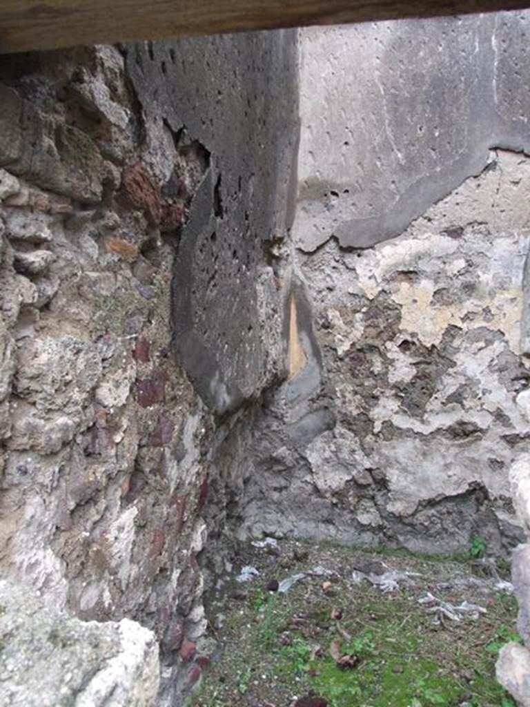 VI.11.9 Pompeii. March 2009. Room 14, north-west corner.
According to Boyce, in a room preceding the kitchen, low down in the west wall was a lararium painting done on a red background.
It showed Fortuna, crowned and wearing a whitish tunic and mantle standing holding a cornucopia in her left and rudder resting upon a globe in her right hand.
Below her coiled a serpent, raising its head towards her.
In the background were plants, above and at the sides were garlands.
Against the wall in front of the painting stood a kind of table for the offerings.
See Boyce G. K., 1937. Corpus of the Lararia of Pompeii. Rome: MAAR 14. (p.51, no.184) 
