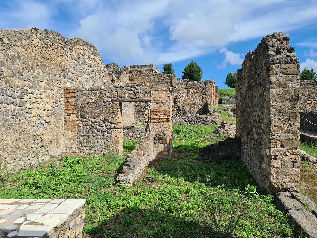 I.2.1 Pompeii. October 2024. 
Looking east across bar-room towards rear rooms leading into I.2.31, with doorway at I.2.32, on right. Photo courtesy of Klaus Heese.


