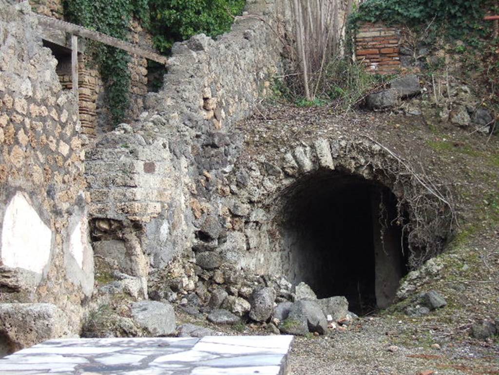 I.2.15 Pompeii. December 2005. Vaulted cistern partly visible from I.2.14. The brick wall at the top of the slope above the cistern marking the end of the corridor from the atrium, together with the remains of the stairs, are the only remains of the area at the west end of the house, that is  steps to upper floor, cupboard, small stable, kitchen and latrine.