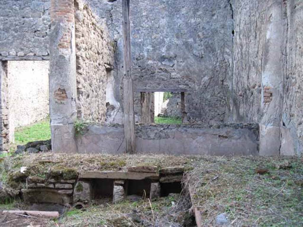 I.2.28 Pompeii. September 2010. Looking south across triclinium towards rear room with window, and doorway to tablinum (on left). Photo courtesy of Drew Baker.
According to Warscher, “Il triclinio occupa la parte opccidentale del pseudo-peristilio. 
Si vedono quattro buchi rettangolari che illuminavano il sotterraneo; l’ingresso a questo ultimo è dalla stanza adiacente (a sinistra nella fotografia no.54 (stanza L)”.

According to Warscher, quoting Mau in Bull. Inst, 1874, p.250/51, she wrote –
“Il peristilio, situate più alto dell atrio a causa del terreno inuguale, ha corridoi di 3 e 3 colonne sui lati S ed E, mentre verso N ed O confina con le case adiacenti (I.2.17; I.2.22; I.2.24).  Le colonne sono di mattoni e di stucco rozzo, color di carne fino all’altezza del muriciuolo che le congiunge, bianco di sopra. La parte occidentale del portico meridionale, posteriormente soltanto, come ci fa testimonianza lo stucco delle colonne, coperto dal muro, ne fu separato e trasformata in una camera, che mediante una porta corrisponde colla camera a sinistra del tablino, mentre verso N con una finestra larga, distante dal suolo m.1,52, si apre sul peristilio. Sotto il pavimento di questa camera v’è un cavo, largo m. 0,98 + 0,67, profondo m. 1,32, rivestito di stucco e di sopra a metà coperto, mentre l’apertura che rimane evidentemente doveva chiudersi con un coperchio. Sifatto cavo, il primo di questa sorta che si sia trovato a Pompei, serviva senza dubbio per conservare tutto ciò, che si voleva difendere dal caldo, facendo così le veci d’una piccola cantina. Sul lato meridionale del peristilio vi è ancora un armadio stretto, aperto verso O, ed il cui fondo viene formato dal muro occidentale della camera a destra dell’atrio, la quale sporge un poco nel peristilio”.
See Warscher T., 1935. Codex Topographicus Pompeianus: Regio I.2. Rome: DAIR, whose copyright it remains.
(translation: "The peristyle, situated higher than the atrium due to the uneven ground, had a walkway of 3 and 3 columns on the south and east sides, while towards the north and west it was bordered with the adjacent homes (I. 2.17; I. 2.22; I. 2.24). The columns were of brick and rough stucco, red-coloured up to a height of a wall that joined them, white above.  As could be seen by the stucco of the columns covered by the wall, the western part of the south portico at the rear only, was separated and transformed into a room, that by means of a door joined with the room to the left of the tablinum, while towards the north, 1,52 m distance from ground,  a large window opened onto the peristyle. Under the floor of this room there was a pit, 0,98m + 0.67 width, 1,32 m deep, faced with stucco and half covered above, while the opening that remained obviously would need to close with a lid. Such a pit, the first of its kind to be found at Pompeii, was undoubtedly to preserve everything, that you wanted to protect from the heat, thus making this the place of a small cellar. On the south side of the peristyle there was still a narrow cupboard, open towards the west, and whose base was formed by the west wall of the room to the right of the atrium, which protruded a little onto the peristyle ".)


