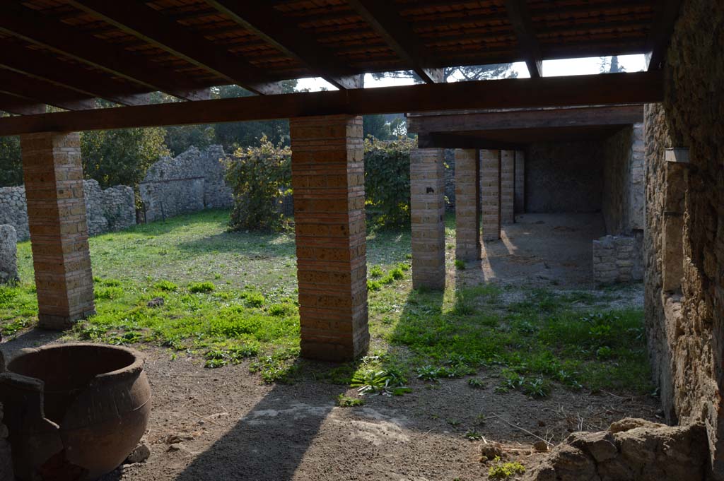 I.5.2 Pompeii. September 2010. Looking north towards remains of masonry podium of lararium. Photo courtesy of Drew Baker.
According to Boyce, there was a ruined lararium in a room on the north-east side of the peristyle. It was a solid podium against the wall, with its three sides painted in imitation marble. There was a painted aedicula on the wall above it.
See Boyce G. K., 1937. Corpus of the Lararia of Pompeii. Rome: MAAR 14. (p.25) 
