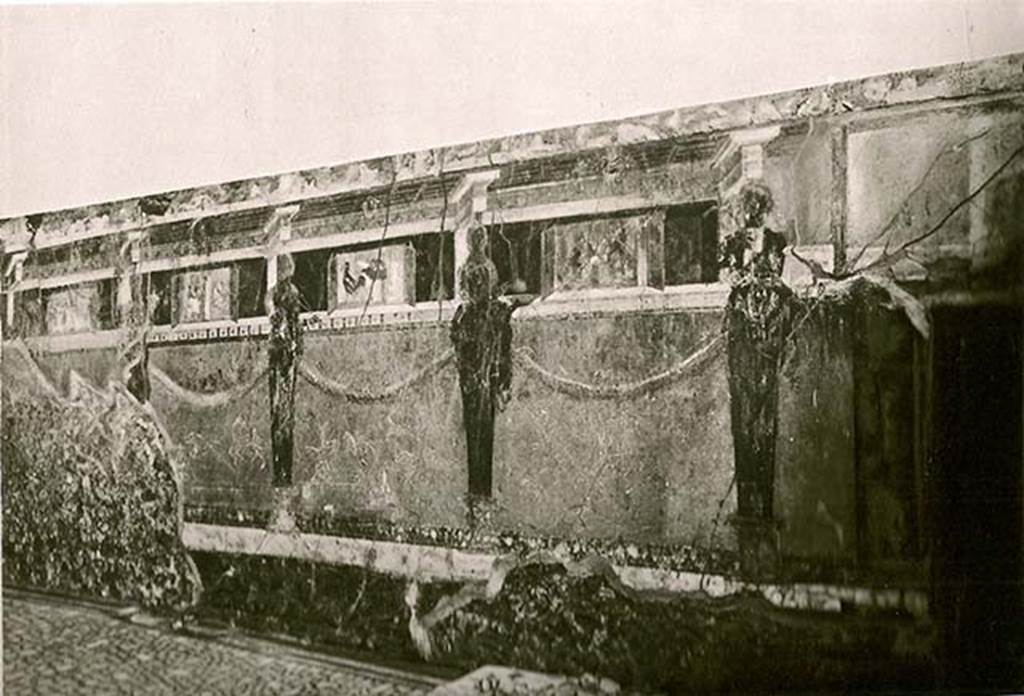 I.6.2 Pompeii. Early 20th C? Old undated photograph of south wall of oecus/triclinium in south-east corner.bRight to left there are four pinax (windowed views with painted shutters).
The Banquet of Silenus.
A Cock with a basket of figs, plums and dates, or which one is on the floor.
The farewell of Alcestis, as she goes to take ferry of Charon to the underworld. 
Another still life, but badly preserved.
See La Rocca, de Vos, de Vos, 1981. Guida Archeologica di Pompei; II Edizione. Milano: Arnoldo Mondadori Editore. p. 204.