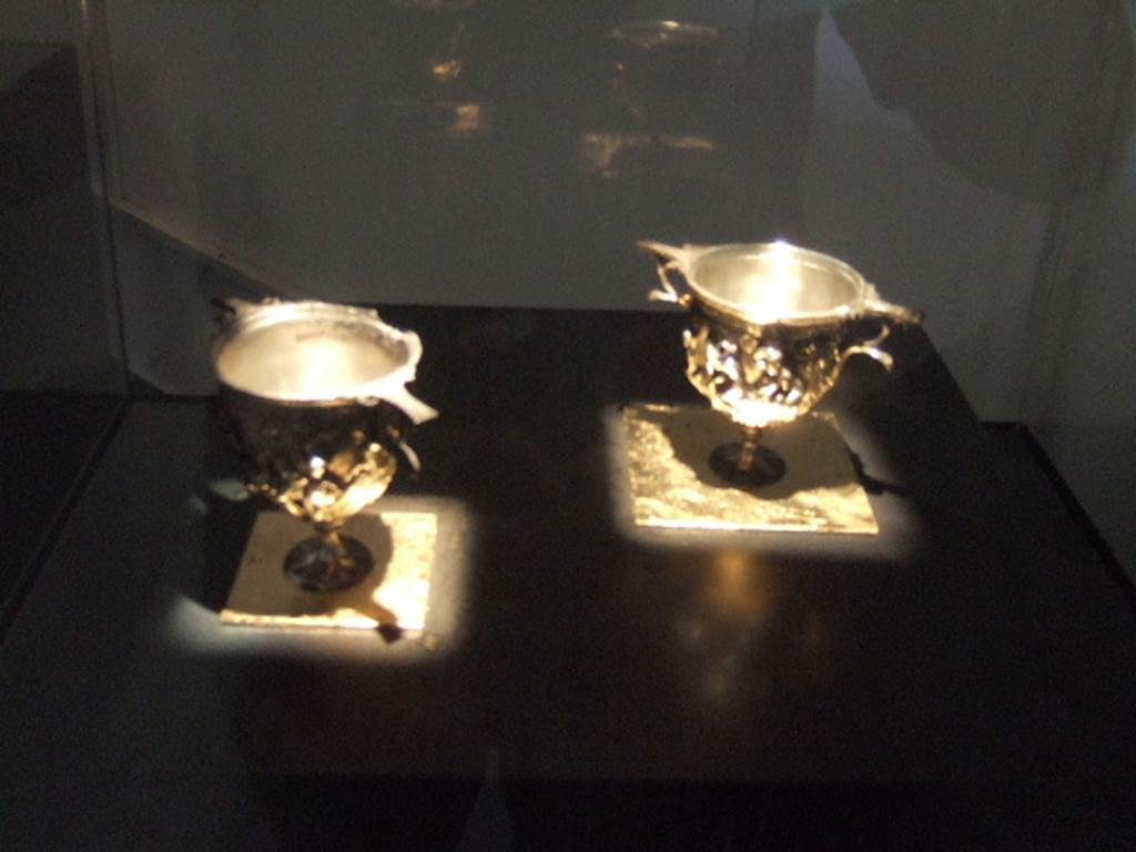 I.10.4 Pompeii. Two double handled calici - scyphi (at front), silver cups decorated with olives. Part of the 115 pieces of Silver found in a chest in the underground storerooms. Now in Naples Archaeological Museum. Inventory numbers 145514 and 145513. See Guzzo, P. (A cura di), 2006. Argenti a Pompei. Milano, Electa. p.204.