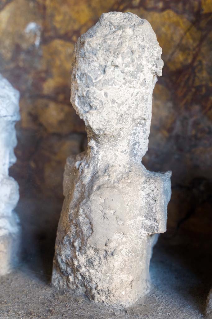 I.10.4 Pompeii. April 2022. 
Alcove 25, detail of plaster cast, on the left, on the lararium or domestic shrine. (Image 1). 
Photo courtesy of Johannes Eber.
