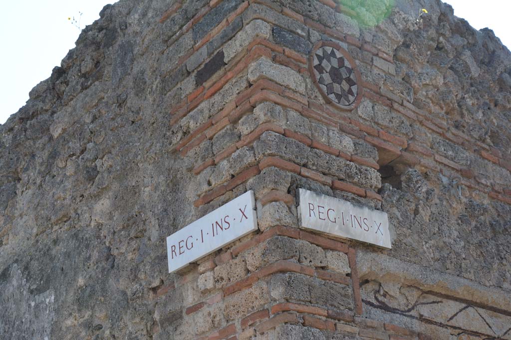 I.10.9 Pompeii. April 2017. 
Corner of insula I.10, Vicolo del Menandro, on left, and coloured terracotta plaque above doorway of I.10.9, in Vicolo del Citarista, on right.  
Photo courtesy Adrian Hielscher.
