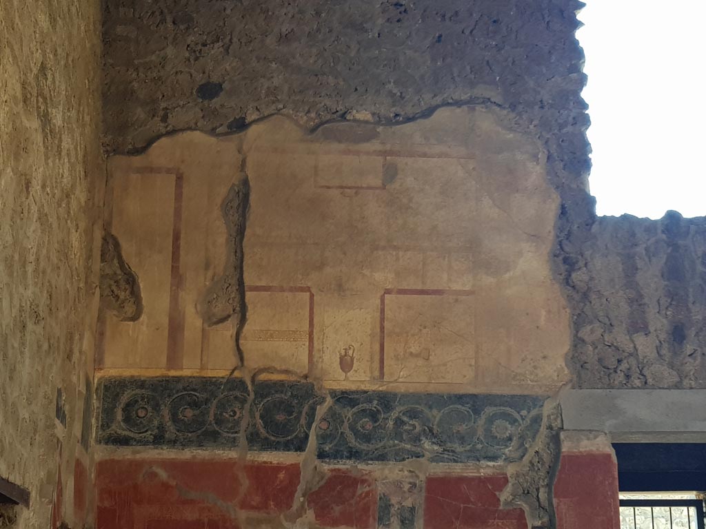 I.10.11 Pompeii. October 2022. 
Room 2, west wall of atrium. Painted wall at south end above room 3 doorway. Photo courtesy of Klaus Heese. 
