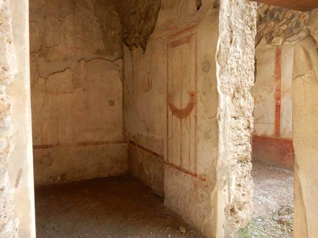 I.11.1 Pompeii. May 2015. South wall of the cubiculum. Photo courtesy of Buzz Ferebee.  “The room to the east of the thermopolium, (room b) and communicating with it, was a cubiculum with rather neglected decorations of the IV Style, where only a few fragments of the barrelled ceiling could be recovered.  On the eastern side was the recess for the bed and, in the cocciopesto floor, a central decoration of a chessboard in diamond shapes, made with minute white marble tesserae.   In the centre of the largest panels of the walls were three medallions of 0.28m diam.   In the south wall, the head of Diana with diadem facing front, with bow raised high in the left hand, and quiver behind the right shoulder, and the other two from the north wall were of the head of Bacchus, crowned with vine leaves facing front, and with slender staff on the right shoulder, and of nude Apollo in threequarters looking right, with his lyre held between his hands.  In the smaller space (east wall), flying towards the centre, two naked Cupids, one holding   a long lamp and a tray, and the other something like an umbrella.”
See Notizie degli Scavi, 1913, p.249-50.
(L’ambiente ad est del termopolio, e con esso comunicante (b), era un cubicolo con decorazioni piuttosto trascurate di IV stile, del cui soffitto a botte soltanto pochi frammenti si sono potuto recuperare. Nel lato orientale era il rincasso per il letto e, nel pavimento di cocciopesto, una scacchiera centrale a reticella di rombi, fatta con tesserae minute di marmo bianco. Al centro dei maggiori riquadri delle pareti, tre medaglioni di 0.28m di diam. esibiscono l’uno (parete sud) il busto di Diana, di fronte, diademata, con arco nella sinistra levata in alto e turcasso dietro la spalla destra, e gli altri due (parete nord) i busti di Bacco di fronte, coronato di foglie di vite e con esile tirso sulla spalla destra, e di Apollo, in terza a destra, nudo, con la cetra stretta fra le mani.
 Negli spazi minori (parete est) convergono, volando verso il centro, due Eroti nudi, reggenti l’uno una lunga face e un vassoio, e l’altro come un ombrello.)
