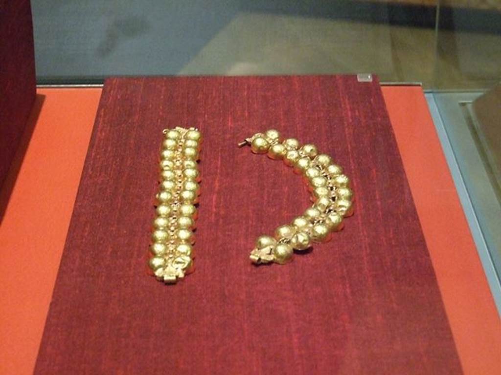 I.11.6 Pompeii. Two gold bracelets with twelve pairs of hemispheres linked together by articulated links with a cylindrical body.
Found in a bronze arca (chest) in the south-east corner of the atrium.
SAP 10759a and 10759b.  
Photographed at “A Day in Pompeii” exhibition at Melbourne Museum. September 2009.
See Mileti M. C., 2000. La casa I, 11, 6-7 a Pompeii: Rivista di Studi Pompeiani XI, p. 110.
