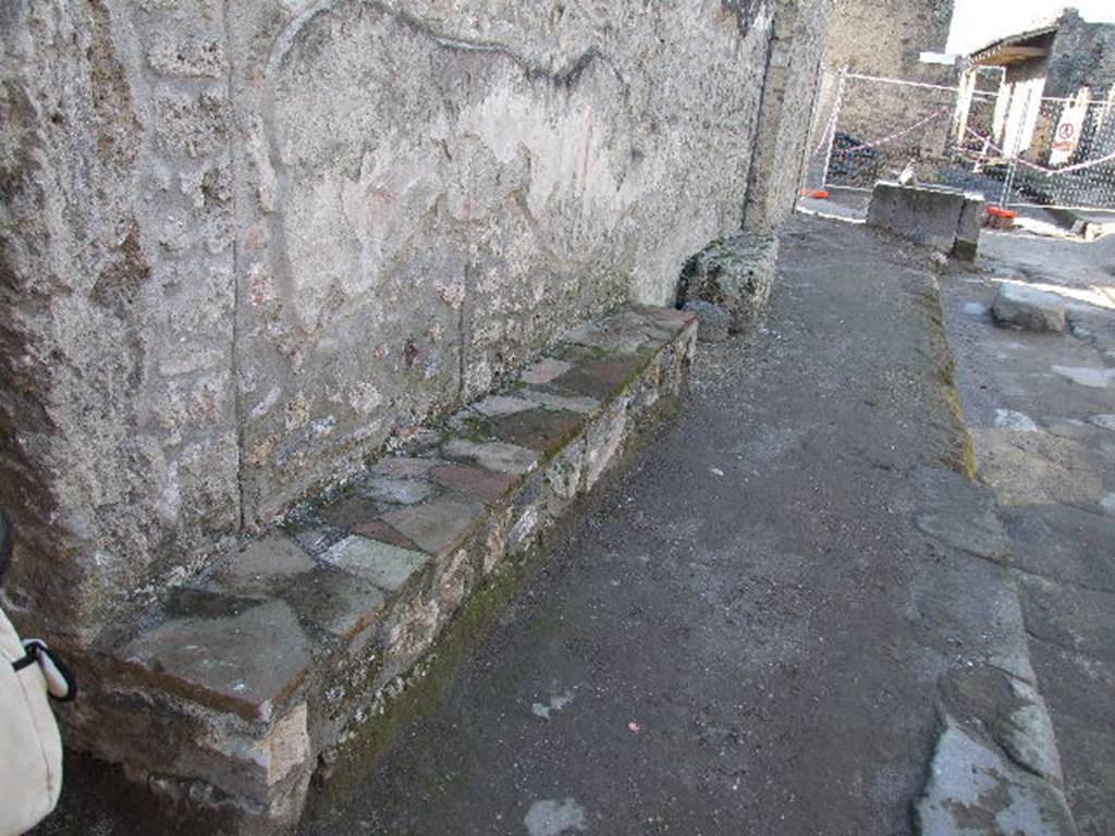 I.16.3 Pompeii. December 2006. Looking west along façade and at plaster on outside wall, and benches on Via di Castricio.
