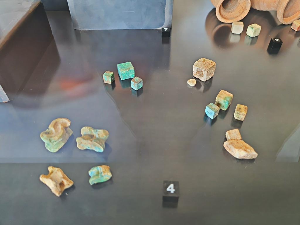 II.1.6, Pompeii. March 2024.
No.4 – Game set consisting of bronze and bone dice and astragals. Photo courtesy of Giuseppe Ciaramella.
On display in exhibition in Palaestra entitled – “L’altra Pompei, vite comuni all’ombra del Vesuvio”. 

