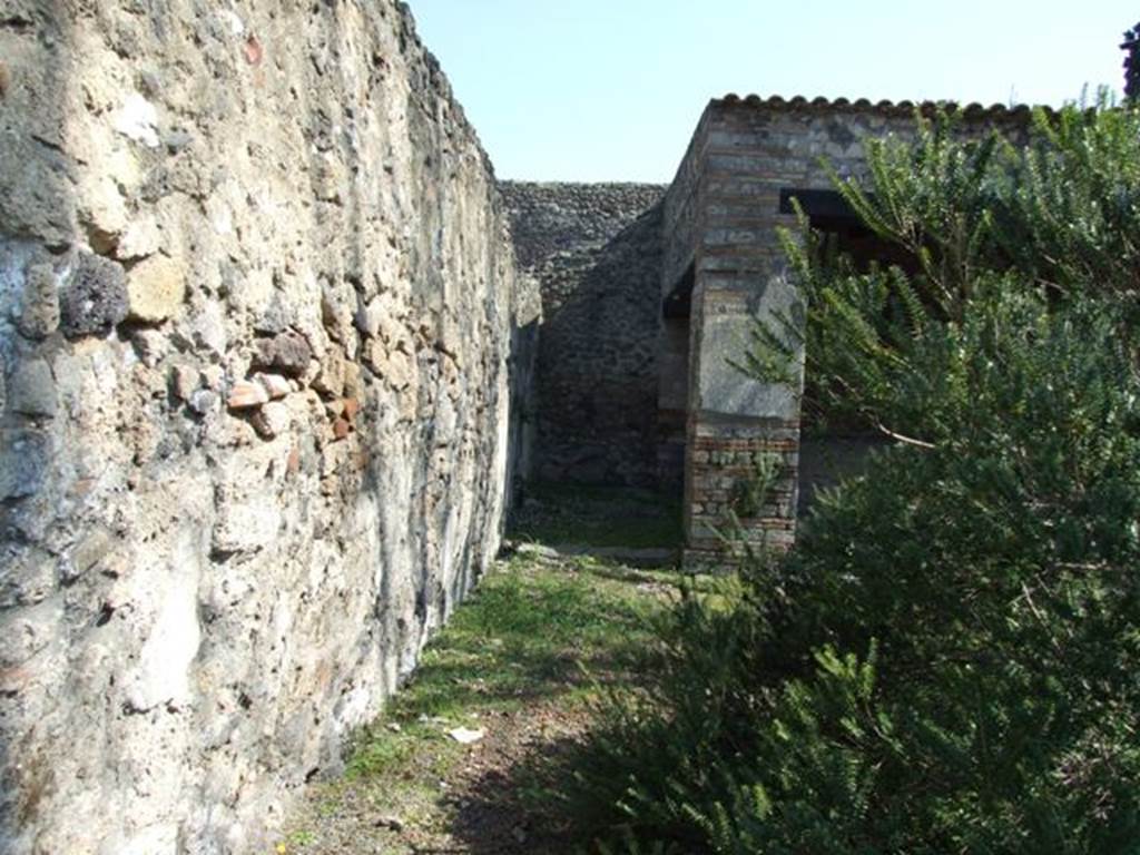 II.1.12 Pompeii. March 2009. Looking east along the north wall to sacellum, and area of storeroom. According to Jashemski, to the left (north) of the sacellum were 2 storerooms. To the right (south) were 2 roughly furnished rooms in which various cult objects were stored 
(see photos of rooms on east side of peristyle, above and in Pt.2).  
Among the objects found in the rooms off of the sacellum were two almost life-sized bronze right hands. Hands such as these were associated with the worship of Sabazius. Various bronze as well as terracotta lamps: a bronze statuette of a youth: and a small bronze dog were also found.  Near the altar were 2 unusual, squat terracotta vases which had a little bowl attached to the rim above each handle. See Jashemski, W. F., 1993. The Gardens of Pompeii, Volume II: Appendices. New York: Caratzas. (p.76)
