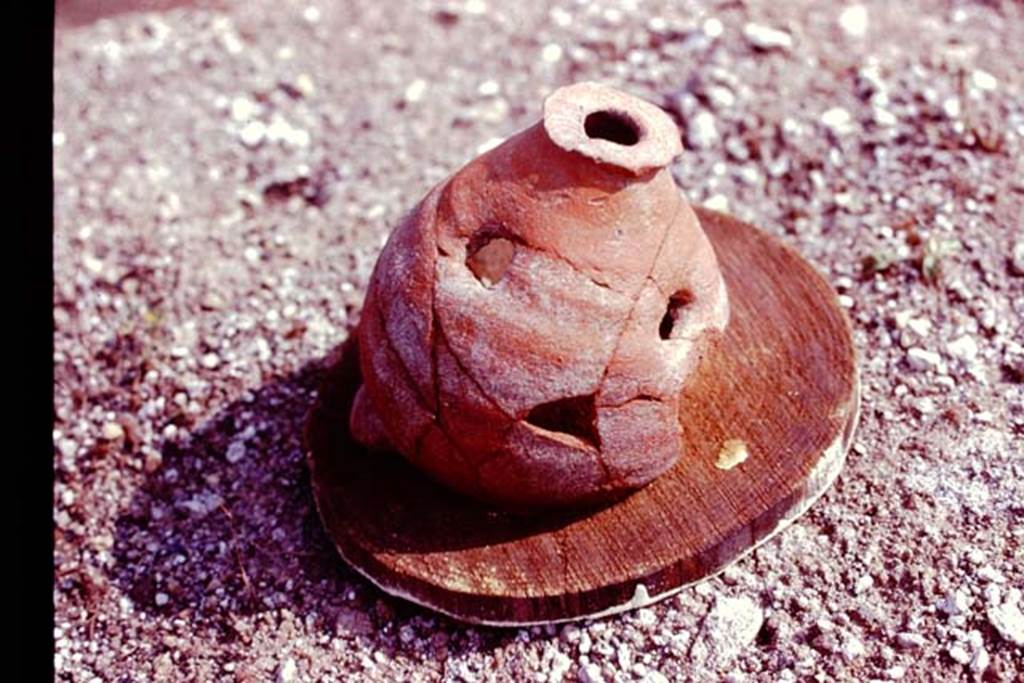 III.7 Pompeii. 1976. Broken planting pot with one hole in the bottom and three holes in its side. Photo by Stanley A. Jashemski.   
Source: The Wilhelmina and Stanley A. Jashemski archive in the University of Maryland Library, Special Collections (See collection page) and made available under the Creative Commons Attribution-Non Commercial License v.4. See Licence and use details. J76f0471
