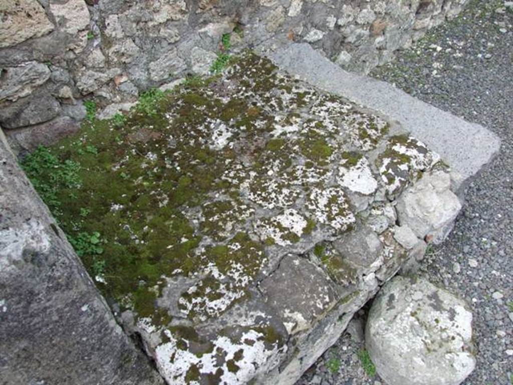 V.2.13 Pompeii. March 2009. South-west corner of thermopolium, and masonry hearth or base. 
According to Boyce, 
“Above the hearth in the south-west corner is a poorly preserved lararium painting: The Genius is represented sacrificing at an altar; on each side originally stood a Lar, only the one on the right being now preserved; further to the right a single serpent approaches an altar.
The above description is taken from Sogliano published in 1879; the descriptions of this house in Rom. Mitt and Not. Scavi, published fifteen and seventeen years later, mention only an altar is visible in a painting, but presumably all refer to the same shrine.”
According to NdS, this thermopolium had a sales counter and a small hearth.
On the west wall Sogliano could see the remains of a painted lararium, with a serpent sliding towards an altar on the left.
At the rear was located the room for the customers, which was bordered by a corridor to the latrine.
See Notizie degli Scavi di Antichità, 1896, (p.438)
