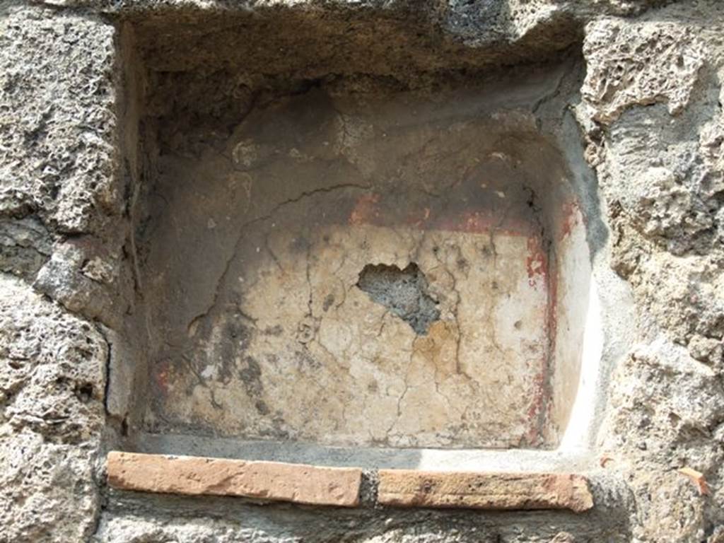 V.2.14 Pompeii. March 2009. Niche Lararium in north wall of shop.
According to Boyce, this niche had a projecting floor and its inside walls were coated with white stucco and outlined with red stripes.
He also mentioned that in Mau’s (1894) description of V.2.13, a cylindrical altar of travertine was found in the rear room.
Boyce thought there was confusion between the text and the plans of the rooms, and in fact the altar was found in V.2.14.
When the book was written, the altar was on display in V.2.14.
However, the Notizie degli Scavi di Antichità, 1896, p. 438, does not record the discovery of this altar.
See Boyce G. K., 1937. Corpus of the Lararia of Pompeii. Rome: MAAR 14. (p.34, no.93) 

