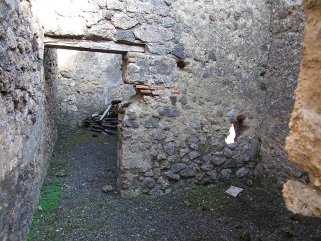 V.2.c Pompeii. December 2007. Room “c”, which was once the kitchen. 
Looking towards rear of room and doorway to room “d”.
In the south-west corner were traces of lararium painting.
In the south-east corner, between the two doors, was a fusorium, missing its hearth, probably, removed in antiquity. 
Also found were some amphora, one with the inscription in red M · I · L, and six others with inscriptions, a small amphora and a bowl made of clay.

Also in this house, according to Boyce, there was a second faded lararium painting in the south-west corner of the second room behind the bar. [=”c”?]
Each wall in the corner, the south and the west, had a panel of white stucco. 
On each was painted a serpent approaching the altar.
Presumably, in the corner between them would have been the altar. 
Above the serpents were garlands.
See Boyce G. K., 1937. Corpus of the Lararia of Pompeii. Rome: MAAR 14. (p.36, no.100).  
