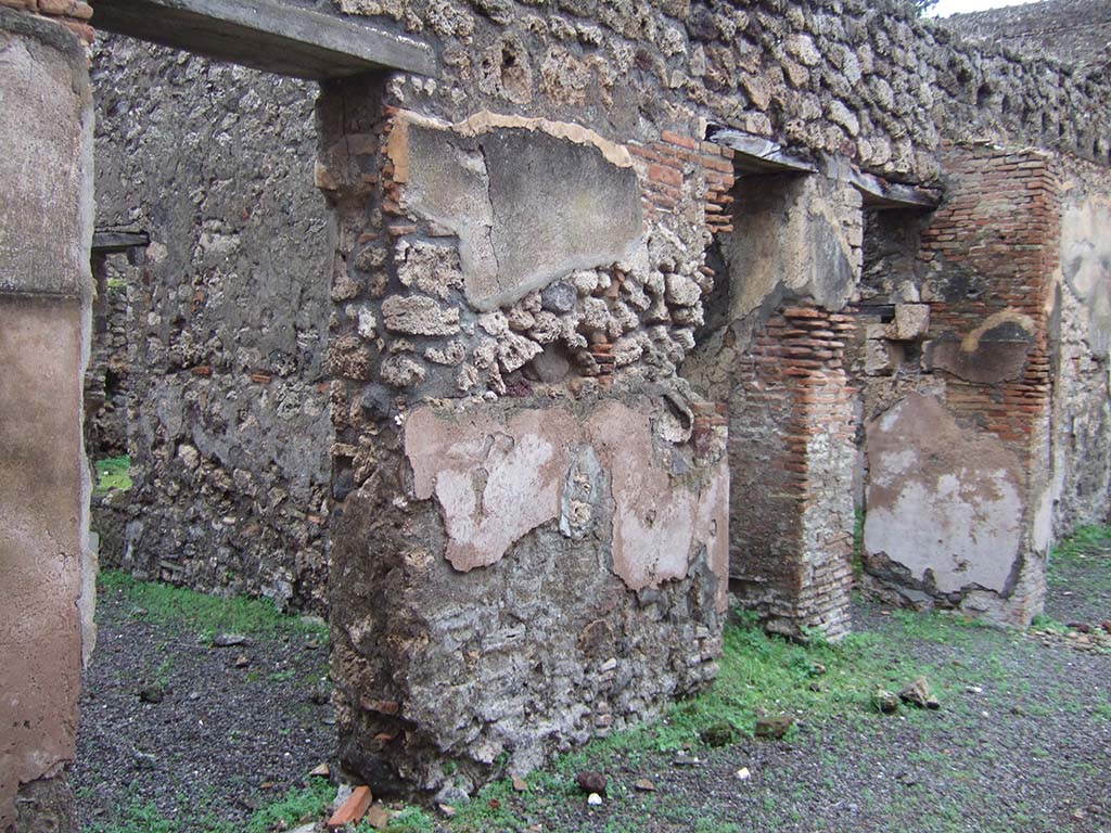 V.2.e Pompeii. December 2005. Three doorways on the north side of the atrium. 
The left doorway leading to a room with a window in the east wall overlooking the garden.
The middle doorway leading to steps to upper floor with recess beneath.
The last doorway, on the right, leading to the garden area, the kitchen and a cubiculum.
See Eschebach, L., 1993. Gebäudeverzeichnis und Stadtplan der antiken Stadt Pompeji. Köln: Böhlau. (p.136)
