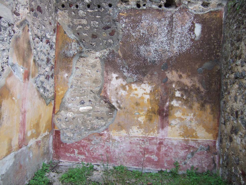 V.2.h Pompeii. December 2005. Room ‘m’, looking towards the east wall with round holes for roof supports. 
The zoccolo/dado was red. 
The walls were yellow edged with “carpet” borders which are only just visible and separated into three panels by narrow red compartments.
