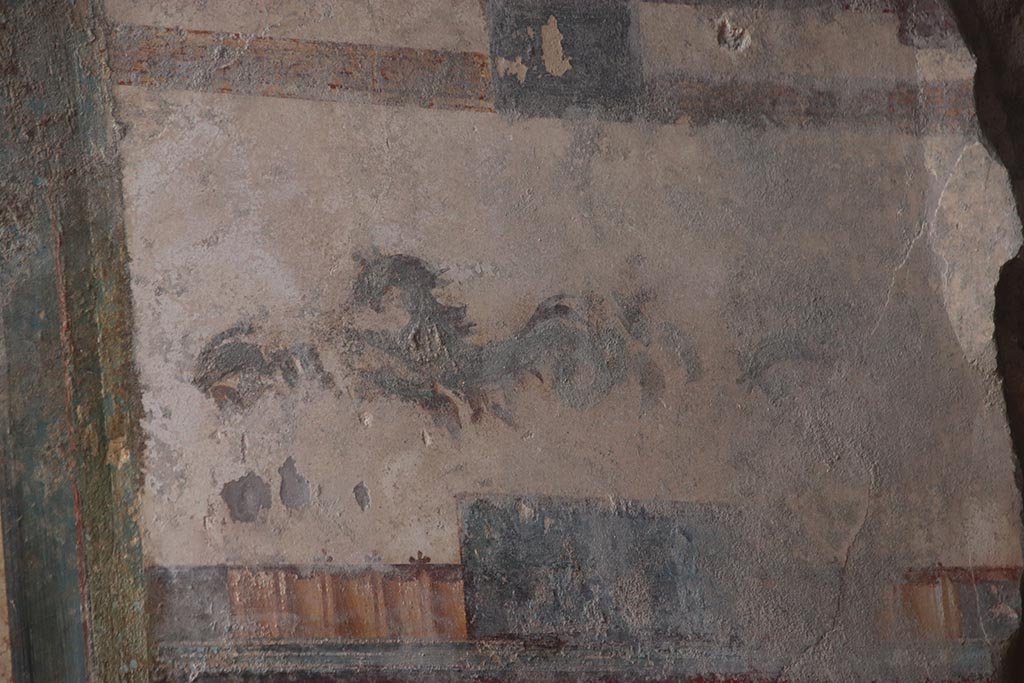 V.6.12 Pompeii. October 2024. 
Detail of dolphin and marine animal from upper panel on east side of central painting of Priapus. Photo courtesy of Klaus Heese.
