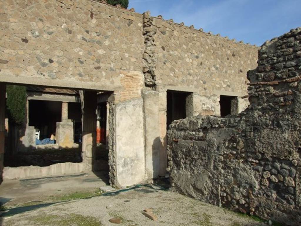 VI.1.7 Pompeii. December 2007. Room 10, looking through north doorway into room 13, the peristyle, and towards the north-east corner with doorway through to room 11. 
According to PAH, 1, 2,  (p.22) and (Addendum on page 167)
29 Luglio 1784 In questa settimana si e impiegata l’opera in trasportare la terra depositata dallo scavo delle due stanze notate nel passato rapporto. Nella stanza dove resta un quadretto nel pavimento come specchio, vi stanno due porte contigue l’una all’altra, che corrispondono al cortile della medesima abitazione, le quali ho stimato pulire per osservarne le soglie. Nella piu grande porta era un quadrilungo formato da un fascia di musaico nero, e l’interno del quale e di musaico bianco; veniva ornato da due delfini di musaico nero e nel mezzo un.ancora. Ma sendo mancante una quasi meta di detta soglia a causa delle ruine, esiste solo un delfino con l’ancora.  Nell’altra porta piccola vi era la soglia di una pietra nera, nelle quale si sono trovate due piastre con tondi per il gioco delle porte.
(translation – 29th July 1784
For this week, we have transported the earth deposited by the excavation of the two rooms noted in the past report. In the room where there is a little square in the floor as a mirror, there are two neighbouring doorways, one next to the other, which link to the courtyard of the same dwelling, I have cleaned the thresholds in order to look at them.   
In the biggest doorway was a long square formed by a band of black mosaic, and inside of which was white mosaic. It was decorated with two black mosaic dolphins and in the middle was an anchor. But as nearly one half of this threshold was missing due to the damage, there exists only one dolphin with the anchor.  In the other small doorway, there was a threshold of a black stone, in which were found two slabs with holes for the play of the door. )
