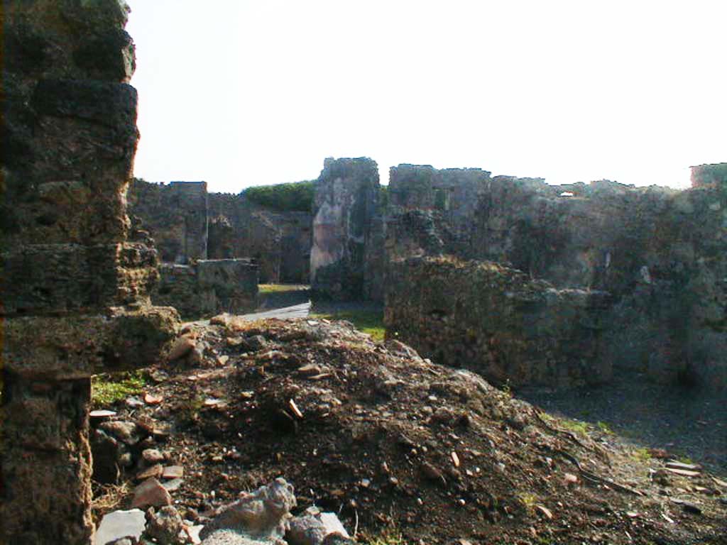 VI.11.7 Pompeii. September 2004. Triclinium, on the left of the entrance, is under the pile of soil.
Looking south-east from entrance, towards tablinum of VI.11.12, at the rear of VI.11.7.
According to Helbig, in the kitchen area there were fragments of a lararium painting.
See Helbig, W., 1868. Wandgemälde der vom Vesuv verschütteten Städte Campaniens. Leipzig: Breitkopf und Härtel. (89).
