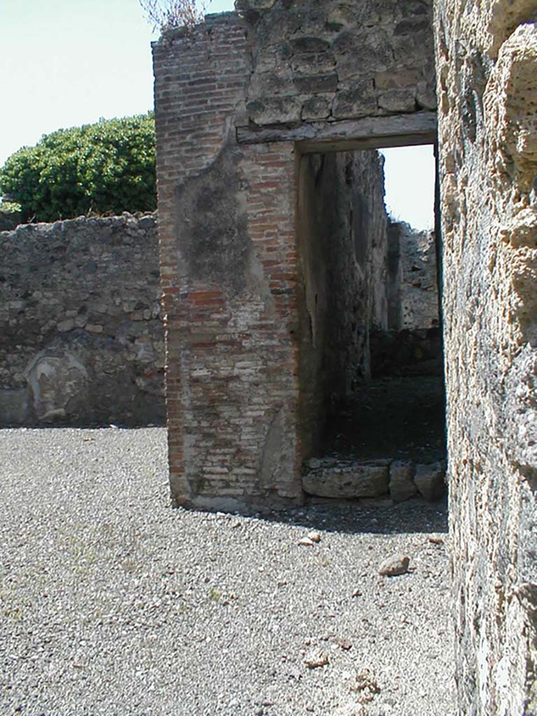 VI.14.30 Pompeii. May 2005. Looking west along north side of atrium towards doorway to stairs to upper floor.