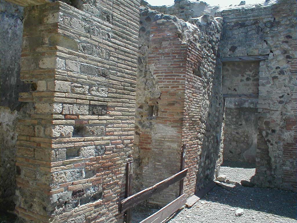 VI.14.30 Pompeii. May 2005. Looking south along east side of atrium.
The entrance corridor or fauces is in the centre, the doorway into VI.14.28 is on the right.
