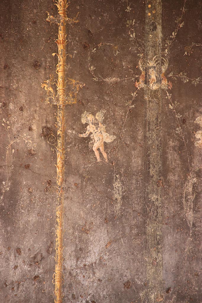 VI.15.1 Pompeii. October 2024. 
Detail of cupid from black painted panel with candelabra from east end of north wall. 
Photo courtesy of Klaus Heese.
