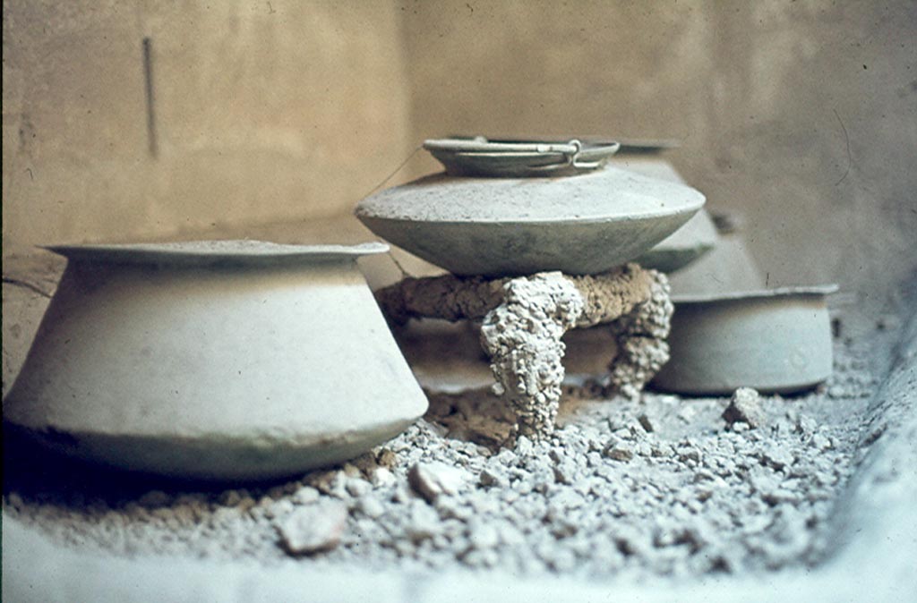 VI.15.1 Pompeii. 1897. 
Watercolour by Luigi Bazzani, looking towards kitchen hearth in service area with pot on tripod on embers and storage pots on floor.
Photo © Victoria and Albert Museum. Inventory number 10-1898.
