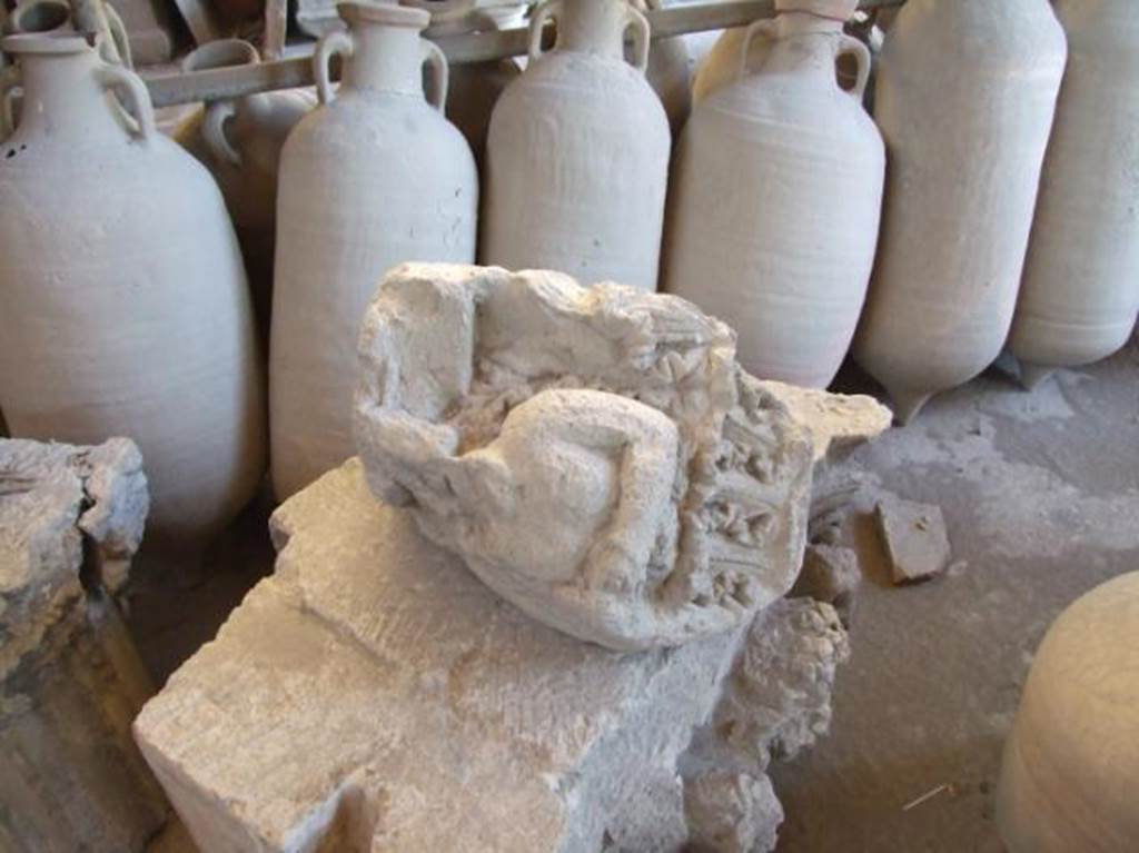 VII.7.29 Pompeii. December 2007. Remains of a capital from VII.4.51 on right, in storage. According to Spano, this damaged capital of Nocera tufa stone was found lying abandoned in a room of VII.4.59 the House of the Black Wall. He suggested it may have been the capital from the right side of entrance VII.4.51 of the House of Ariadne. The capital stone was badly splintered and the details destroyed or damaged. However these few parts were sufficient to show the figures of this capital were similar to that of the other that is very much better conserved. These show similarities in the heads of a satyr and of a maenad in profile, the one near to the other. To the side of each group a small scroll and a line of leaves of vertical acanthuses below, both things characteristic of Pompeian figured capitals.
See Notizie degli Scavi di Antichità, 1910, p.280 and p.282, fig. 12.