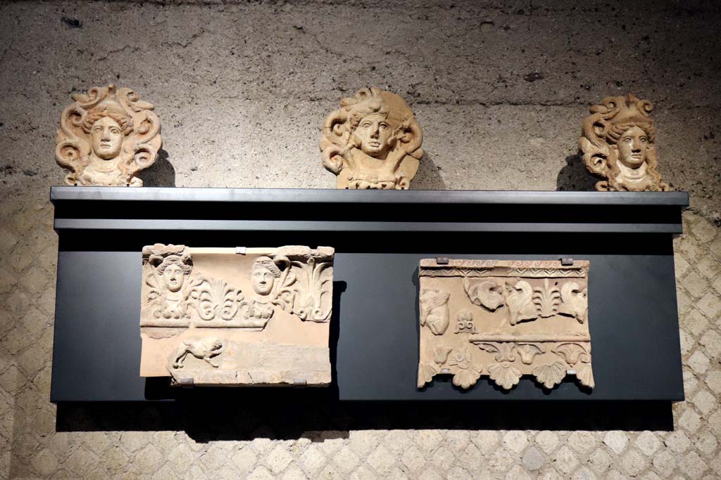 VIII.1.4 Pompeii Antiquarium. February 2021. Terracotta from Doric Temple, at VIII.7.31.
Top: Part of a roof (sima) decorated with female faces alternating with palmettes. 
Lower left: decorative elements of the roof (antefixes) with the head of Athena and Hercules.
Lower right: Roof tiles decorated with sphinxes and vegetal motifs.
Photographed in the Antiquarium. Photo courtesy of Fabien Bièvre-Perrin (CC BY-NC-SA).
