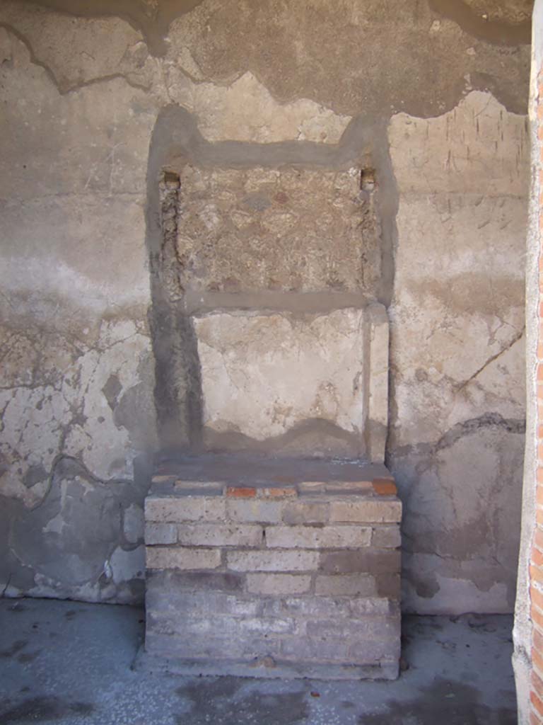 VIII.2.16 Pompeii. September 2005. Remains of aedicula household shrine.
According to Boyce, in the third small room on the south of the atrium, against the south wall stand the ruins of an aedicula.
A masonry podium that was ornamented along the upper edge with a stucco cornice, supported the shrine.
The shrine was built of tufa and coated with white stucco contemporary with the walls of the room.
This was spread not long before the catastrophe.
The inside of the aedicula was divided into two storeys, each supported by two columns and two antae.
The roof was flat and adorned with terracotta antefixes.
One of these was preserved and represented a male face in the centre of a kind of palmette.
Nearby was found a small tufa altar.
See Notizie degli Scavi di Antichità, 1893, p. 48. 
See Boyce G. K., 1937. Corpus of the Lararia of Pompeii. Rome: MAAR 14. (p.74, no.343) 
