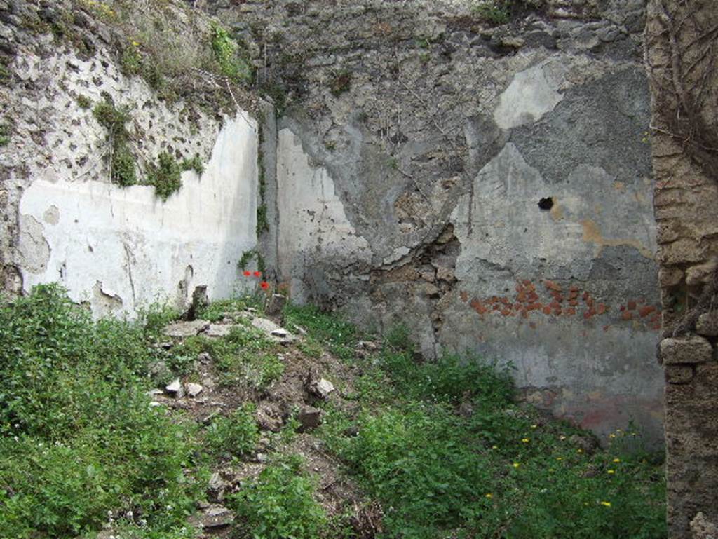 VIII.2.34 Pompeii. May 2006. Room ‘4’, looking towards north and east walls of room on lower level, possibly a triclinium. The floor, now re-filled with rubble from the fallen walls and upper floors, originally was of beaten cement ornamented with white tesserae to indicate the positions of the triclinium couches. The east wall, on the right, shows the signs of a collapsed vaulted ceiling. The painted candelabra III style walls showed a red zoccolo, the middle zone was painted black divided into panels but without any ornamental decoration, ending above with a frieze on a black background between red, white and yellow lines; the upper wall was white.
