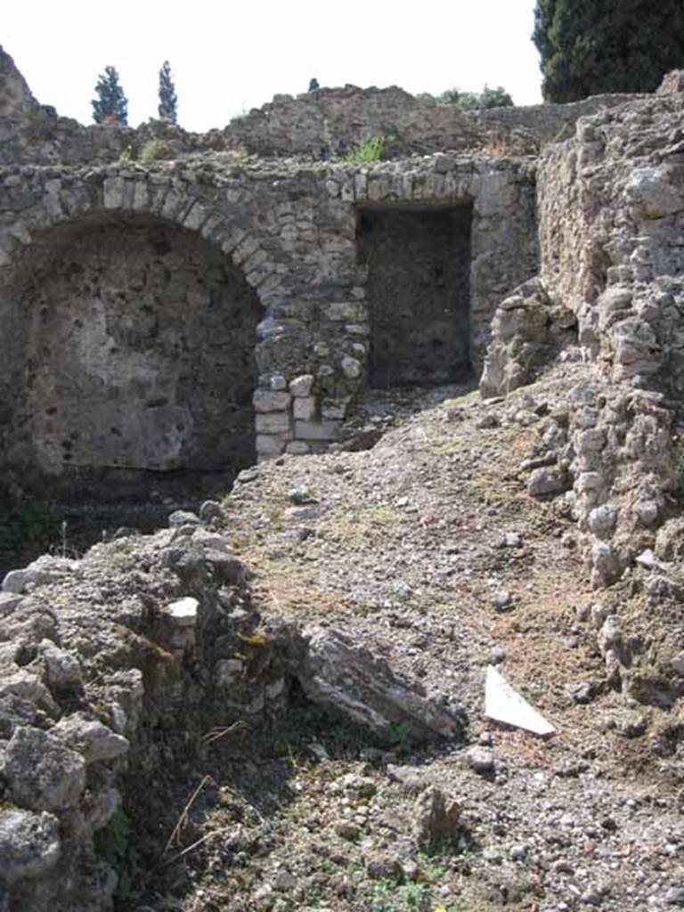 VIII.7.22 Pompeii. September 2010. Looking west from kitchen area of VIII.7.23, into corridor area of VIII.7.22. Photo courtesy of Drew Baker.

The area on the right side of the picture would seem to be the area of the lararium which would have been on the north wall of the corridor, see below. Although Boyce described the lararium as being in an arched niche, his measurements would make the one in the picture above, on the west wall and too big. According to Boyce, in the north wall of a corridor leading from the underground kitchen to the posticum of VIII.7.22, was a large arched niche. This was I.0 metre high, 0.85 wide, 0.50 deep and 0.70 above the floor. The back wall of the niche was painted red, and on it was the figure of Fortuna, clad in a green tunic and yellow mantle. In her left hand she held a cornucopia, and in her right, a rudder. To the left of her feet was a large globe.
The side walls of the niche and the area under the feet of the goddess were decorated with green plants.
See Boyce G. K., 1937. Corpus of the Lararia of Pompeii. Rome: MAAR 14.  (p.78, no:378)

Fiorelli describes, VIII.7.22 as a corridor belonging to VIII.7.24, with stairs to upper floor.  Nearby is the kitchen, in which remains the niche of the Penates, with the image of Fortuna with cornucopia and rudder.
See Pappalardo, U., 2001. La Descrizione di Pompei per Giuseppe Fiorelli (1875). Napoli: Massa Editore. (p.134)
