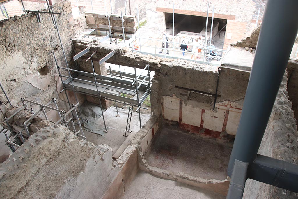 IX.12.7 Pompeii, on left. October 2024.
Looking south-east towards entrance doorway in shop-room 1 onto Via dell’Abbondanza, in centre, and room “c” of IX.12.6 on right. 
Photo courtesy of Klaus Heese.
