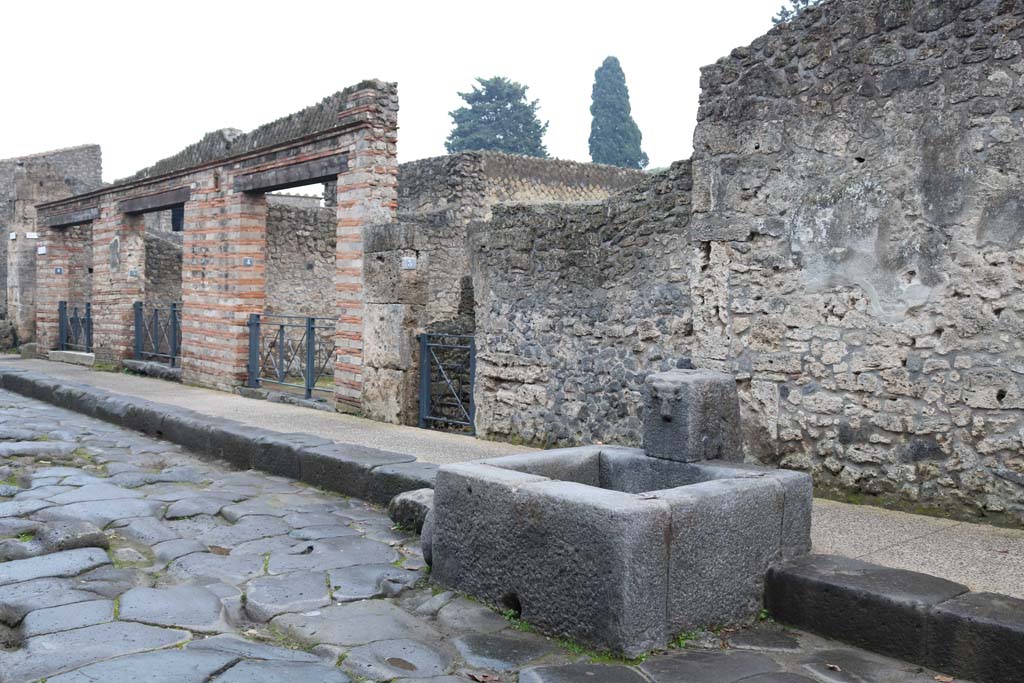 Via dell’Abbondanza, south side. December 2018. 
Looking east between II.1.6, on left to II.1.3, in centre behind fountain. Photo courtesy of Aude Durand.

