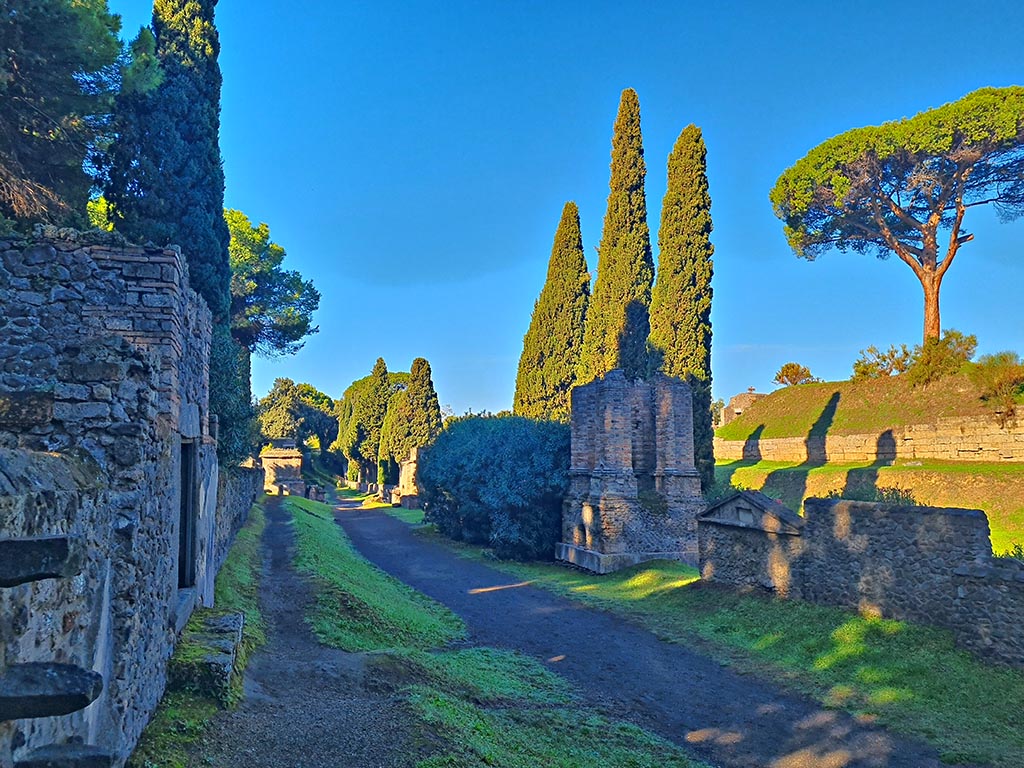 Via delle Tombe, looking west, Pompeii. October 2024. 
Tomb 7ES, with steps built into front wall, on left. Photo courtesy of Giuseppe Ciaramella.
