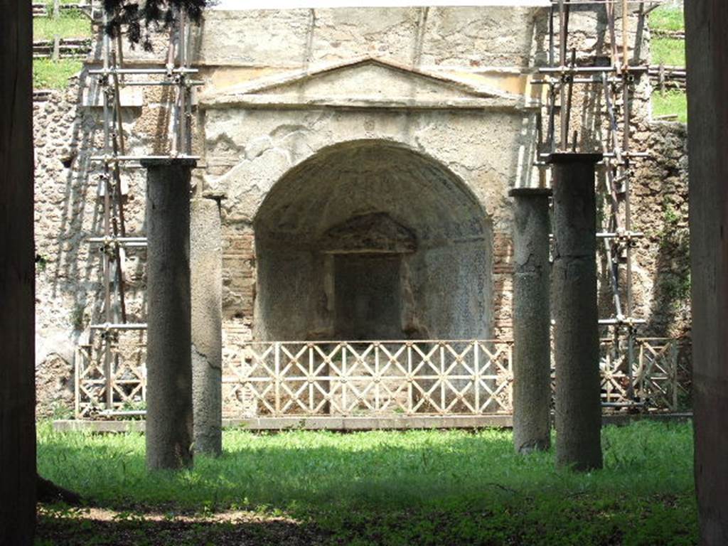 HGE12 Pompeii. December 2006. Mosaic fountain at rear of columns. The four mosaic columns once supported a pergola in the middle of the garden. These were removed and are now in Naples Archaeological Museum. Inventory numbers 9996, 9998, 10000 and 100001. Cement columns now replace the mosaic ones.
