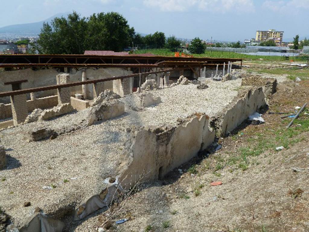 Castellammare di Stabia, Villa San Marco, July 2010. Looking north-east along south side. The small rooms along this side, are still incompletely excavated, and still filled almost entirely with lapilli. Photo courtesy of Michael Binns. It is thought that the main entrance from the street which is still buried, originally gave onto this courtyard with a portico. The entrance would be in the centre of the photo, at the east end. This courtyard would have led to the tablinum and atrium, from its western end.
