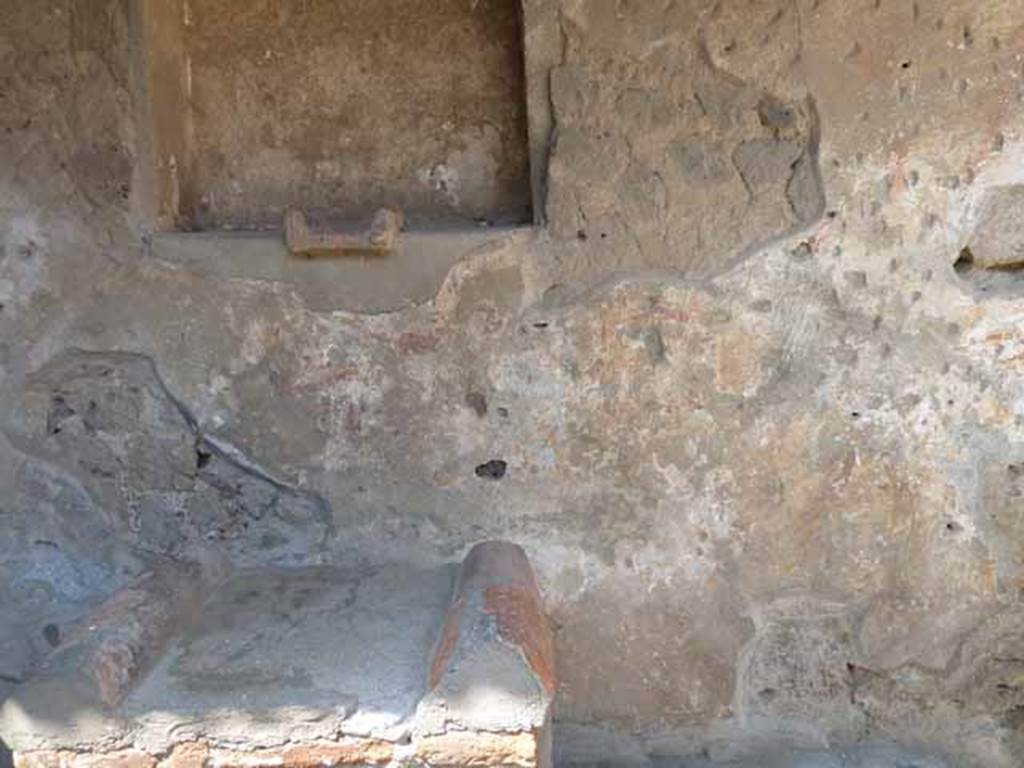 Villa of Mysteries, Pompeii. May 2010. Room 61, north wall of kitchen courtyard near lararium. According to Boyce in 1937, the last layer of plaster had already fallen revealing an earlier layer beneath it, decorated with a figure painting in red and yellow. Maiuri concluded that this was a fragment of the pre-Roman art of the house shrine. When excavated, the paintings were very poorly preserved, and had almost disappeared by 1937. The following description was written by De Petra in Not.Scav, 1910, 141: “Below and to the right of the niche is represented a procession made up of two horsemen, a crowd of people and a tibicen who approaches the altar in the centre, coming from the left.  To the right of the same altar are a Camillus and a second figure.  A still more ancient layer of plaster shows on the right of the niche a strange figure like a Lar pouring from a rhyton of curious shape into a patera (?) held in the other hand; on each side of him are garlands”.
See Boyce G. K., 1937. Corpus of the Lararia of Pompeii. Rome: MAAR 14. (p.97) 
See Maiuri, Villa dei Misteri, 80, and fig. 32.
